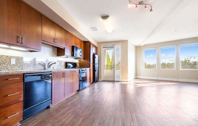 a kitchen and living room with wood floors and wood cabinets