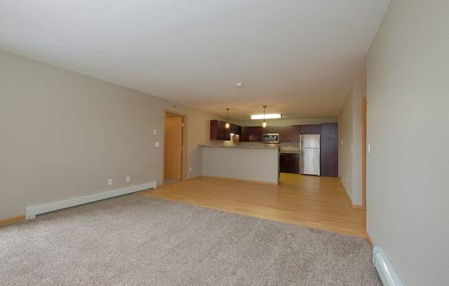 an empty living room and kitchen with a hard wood floor. Fargo, ND Urban Plains Apartments