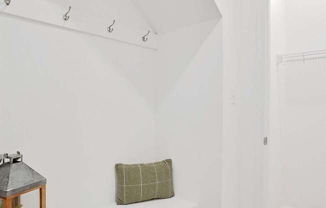 A white bench with a green pillow and a lantern on it.