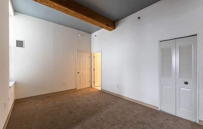 A room with a brown carpet and a wooden beam on the ceiling.