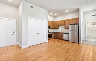 an empty kitchen with wood flooring and a stainless steel refrigerator