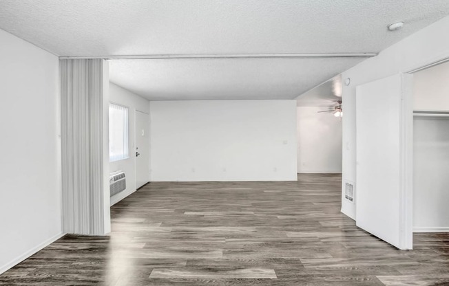 an empty living room with a wood floor and white walls