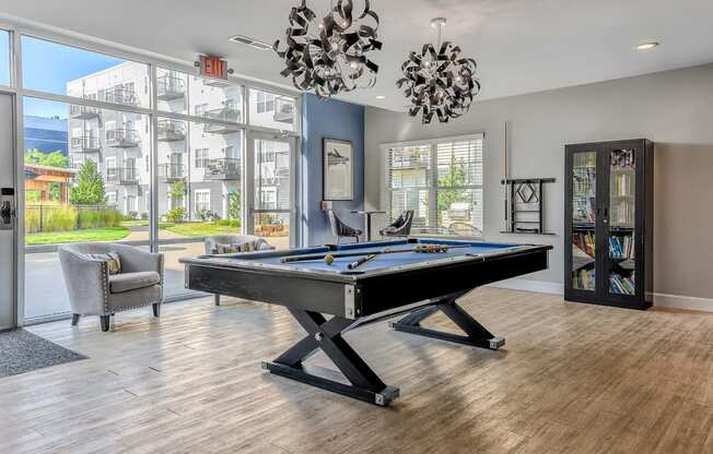 A pool table in a room with a view of the outside.