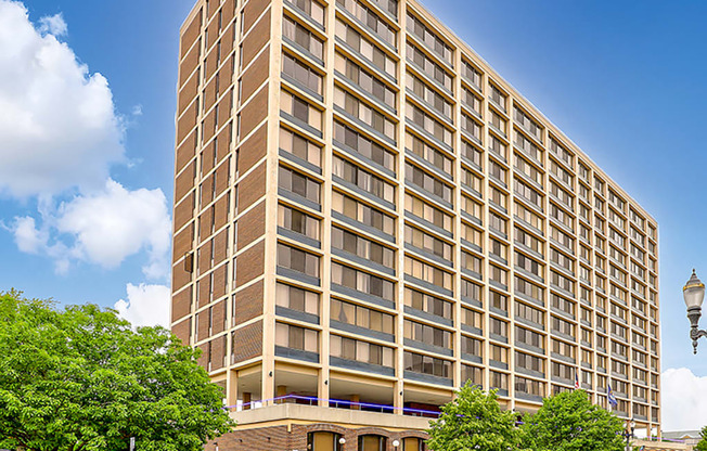 A tall building with many windows and a tree in front of it.