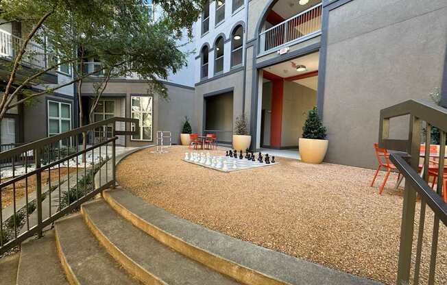 A courtyard with a chess board and chairs.