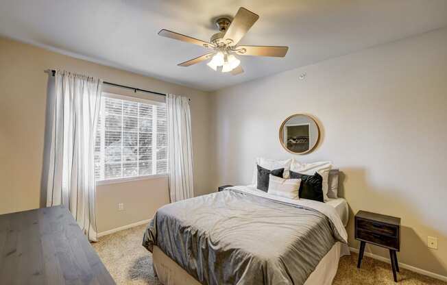 an empty bedroom with a bed and a ceiling fan
