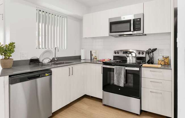 A modern kitchen with white cabinets and stainless steel appliances.