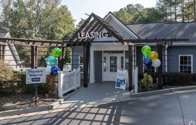 A leasing office is surrounded by balloons and a sign advertises a resident referral.