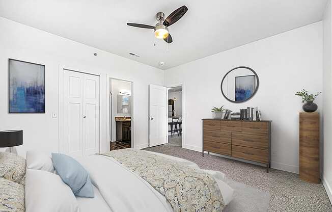 A bedroom with a bed, dresser, ceiling fan.= and ensuite at Dodson Pointe Apartment Homes, Rogers