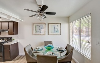 a dining area with a glass table and chairs and a ceiling fan