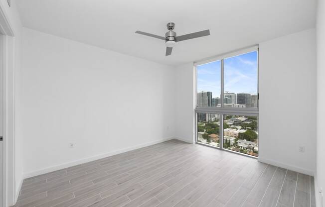 a bedroom with a large window and a ceiling fan