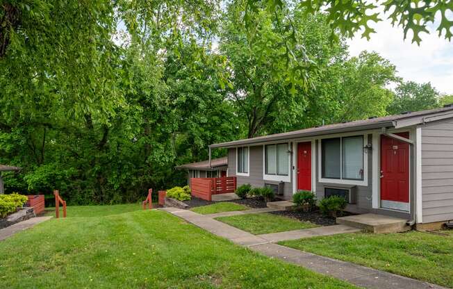 A row of studio and 1 bedroom apartments at The Retreat Apartments in Hendersonville with red doors and green trees in the background.
