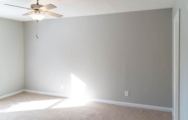 A room with a ceiling fan and sunlight coming through a window.