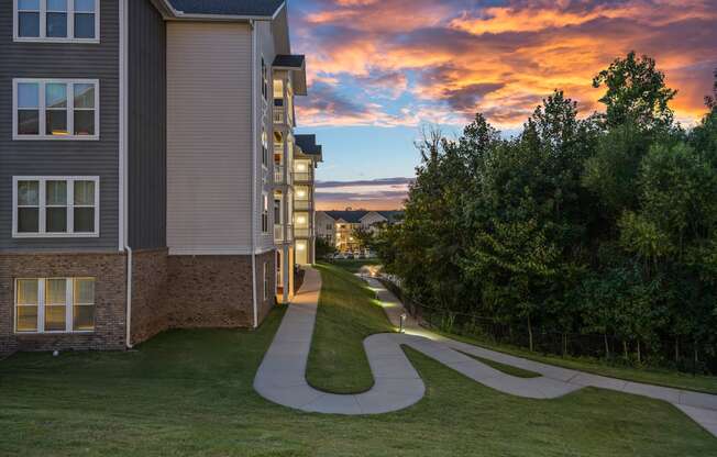 a winding sidewalk between two buildings with a sunset in the background