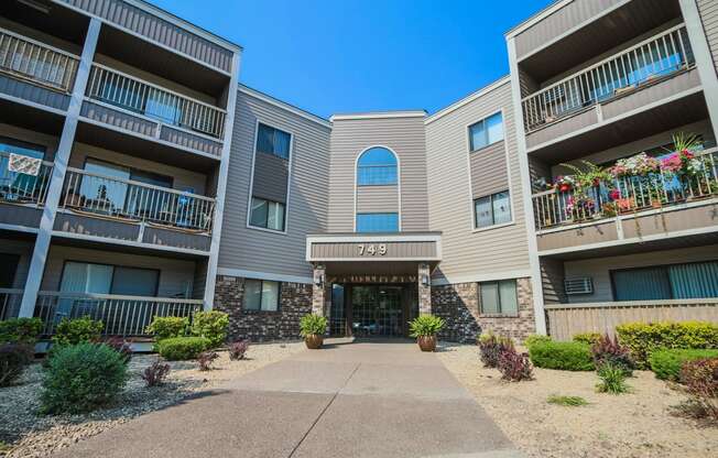 an exterior view of an apartment building with a sidewalk and potted plants