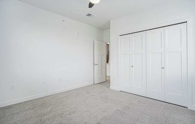 a bedroom with two doors and a carpeted floor at Meadowbrooke Apartment Homes, Grand Rapids, 49512