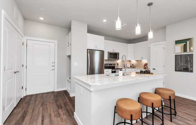 a kitchen with a large island with stools and a refrigerator