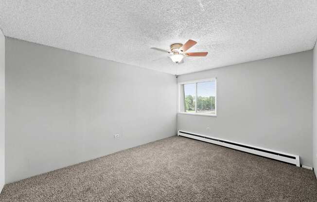 A room with a ceiling fan and a window.