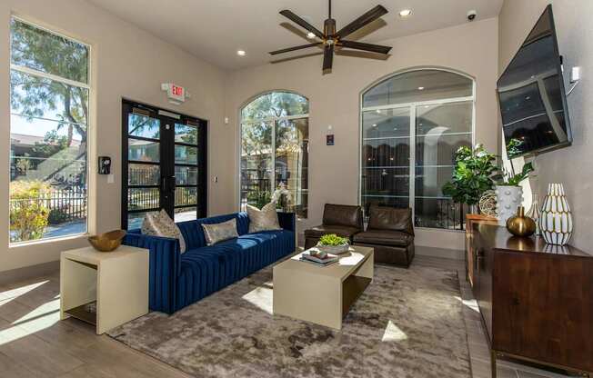 A living room with a blue couch and a ceiling fan.