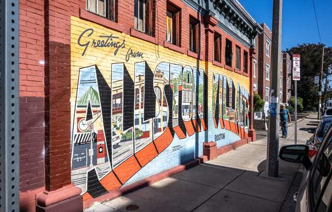 A mural on the side of a building that reads Allston Village, Allston MA