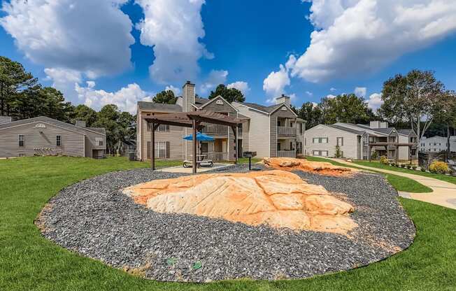 A round gravel area with a sandy patch in the middle is surrounded by houses.