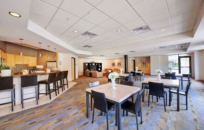 A large room with tables, chairs, and a bar area.