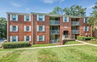 A red brick apartment building with a green lawn in front.