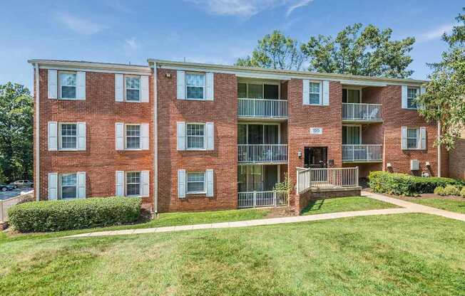 A red brick apartment building with a green lawn in front.