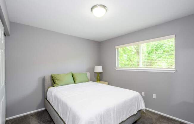 A bedroom with a white bed and green pillows.