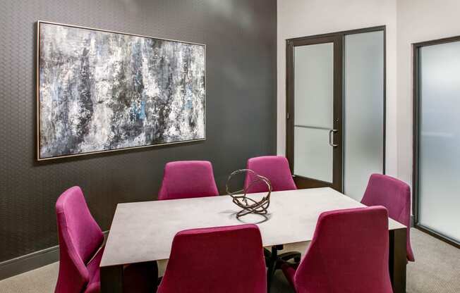 a conference room with a white table and pink chairs