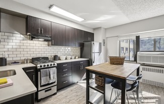 a kitchen with black cabinets and white appliances and a wooden table