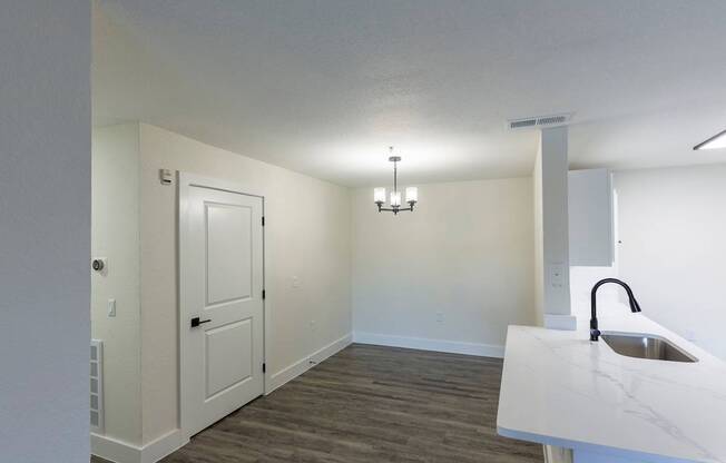 A white sink is on a counter in a room with a door and a chandelier.