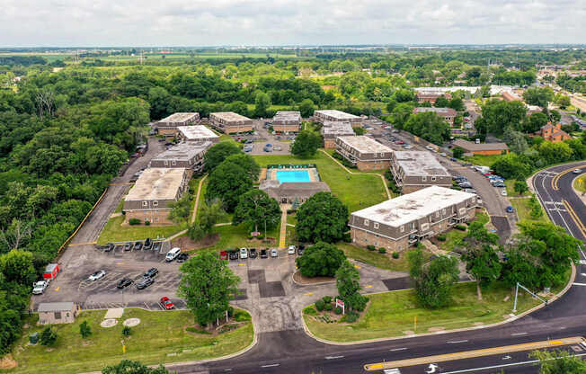 An aerial view of a parking lot with a building and a pool.