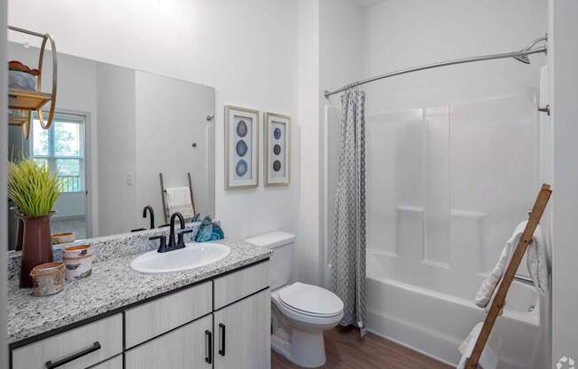 A white bathroom with a toilet, sink, and shower.