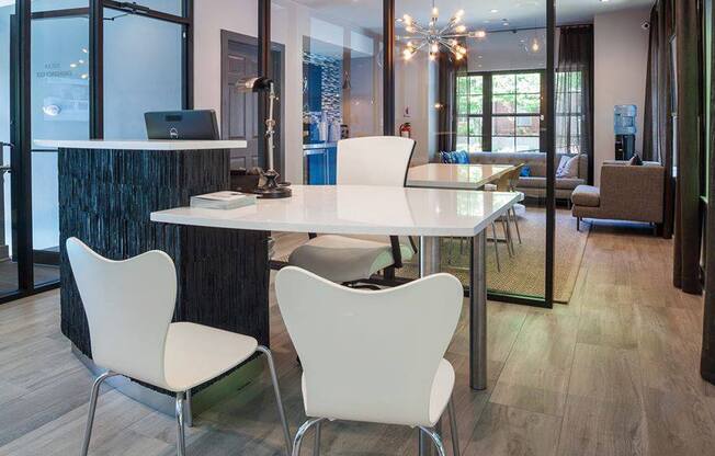 A modern dining room with a glass table and white chairs.