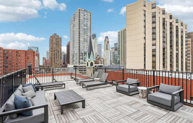A rooftop patio with a table and chairs overlooking a city skyline.