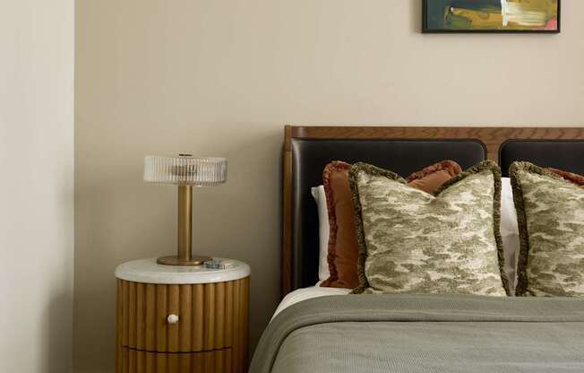 A bedroom with a bed, nightstand, and a painting on the wall.