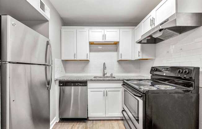 A kitchen with a stainless steel refrigerator and black stove.