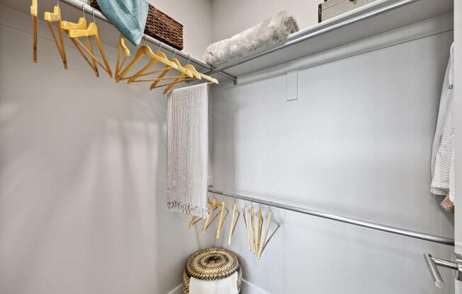 a walk in closet with grey walls and a white closet door with yellow hooks