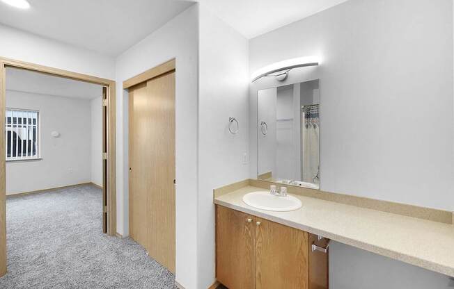 A bathroom with a sink, mirror, and a door.