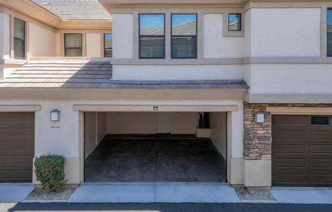 A two-story house with a garage door open.
