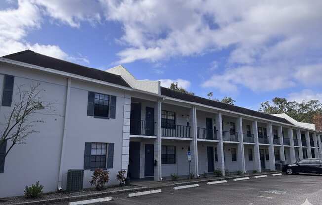 A white building with a black roof and a car parked in front.