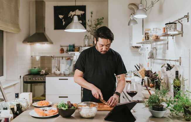 A man is cutting vegetables on a cutting board in a kitchen.
