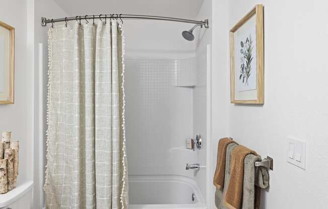 The Edge Milpitas CA a bathroom with white walls and a white bathtub with a shower curtain