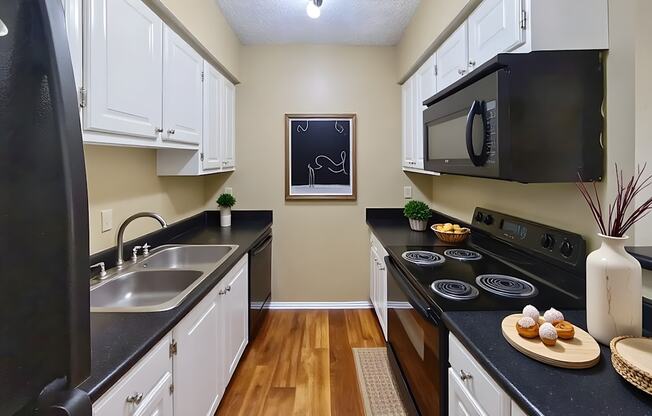 A kitchen with black appliances and white cabinets.