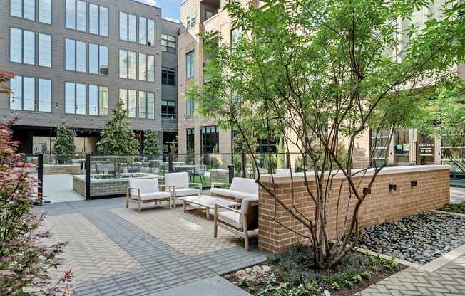 A courtyard with a brick wall and a tree in the middle.