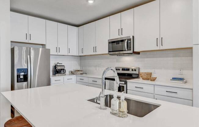 a kitchen with white cabinets and stainless steel appliances