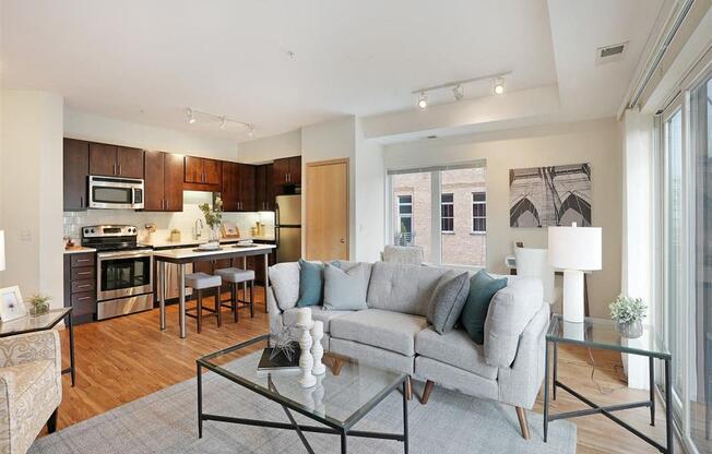 A modern living room with a grey couch and a glass coffee table.