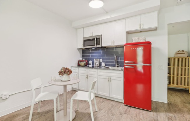 a small kitchen with a red refrigerator and a table and chairs