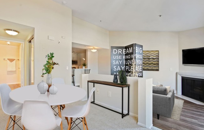 a dining area with a white table and chairs and a fireplace in the background